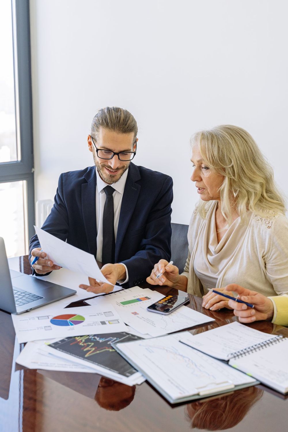 Financial advisor reviewing documents with a client at an office desk