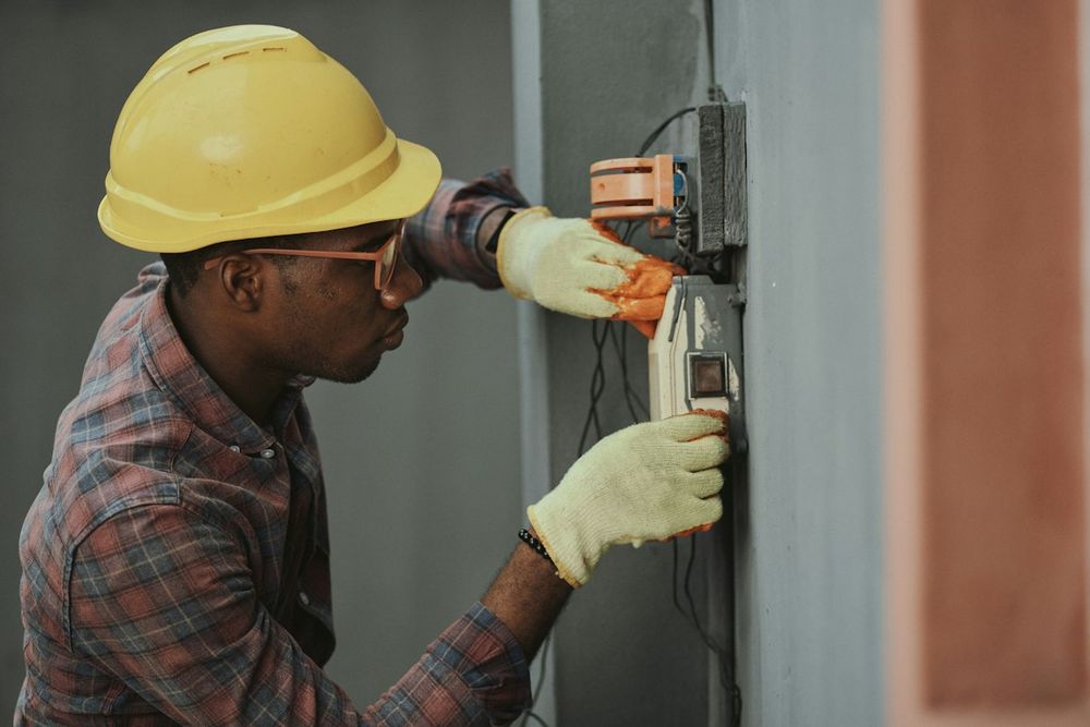 Technician in a hard hat working on an electrical panel at a customer's property
