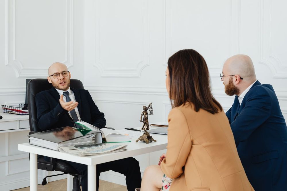 Attorney talking with two clients across a desk in a professional office