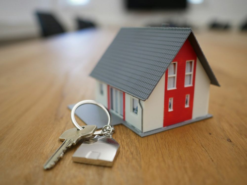 Model house with a set of keys on a wooden table, ready for new owners